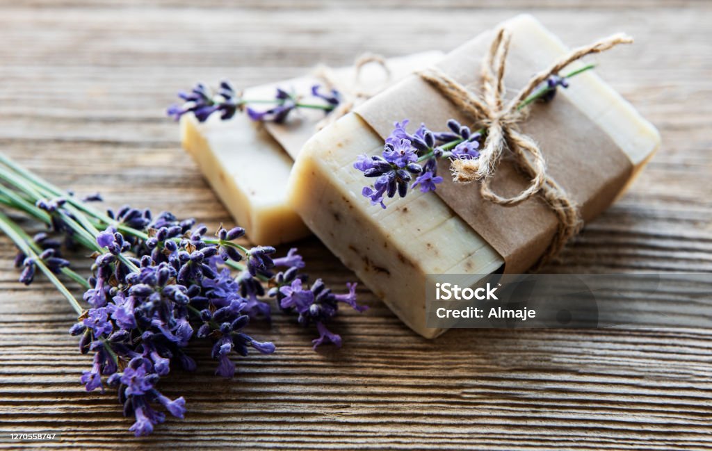 Handmade Soaps and Their Benefits bars of handmade soap with lavender flowers over wood grunge background.